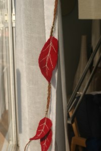 Houseproud homestead projects - close-up of leaves strung on a garland of red flannel flags and red felt leaves.