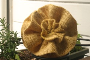 A yellow burlap flower that will be used in a fall-inspired wreath.
