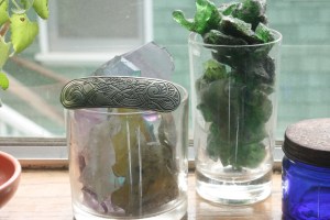 Small glass votive jars on the Houseproud homestead's kitchen window ledge, filled with pretty glass I've found on my hikes.  The silver brooch was a gift from Tom, our neighbor, who passed away recently.  Rest in peace, Tommy - I picture you in a cafe right outside heaven's front gate, giving St. Peter and the folks coming in all sorts of trouble as you sit there sipping coffee, smoking cigarettes, and making friends with the passing dogs.  Save me a chair at the cafe up there, sweetheart.  Miss you lots.